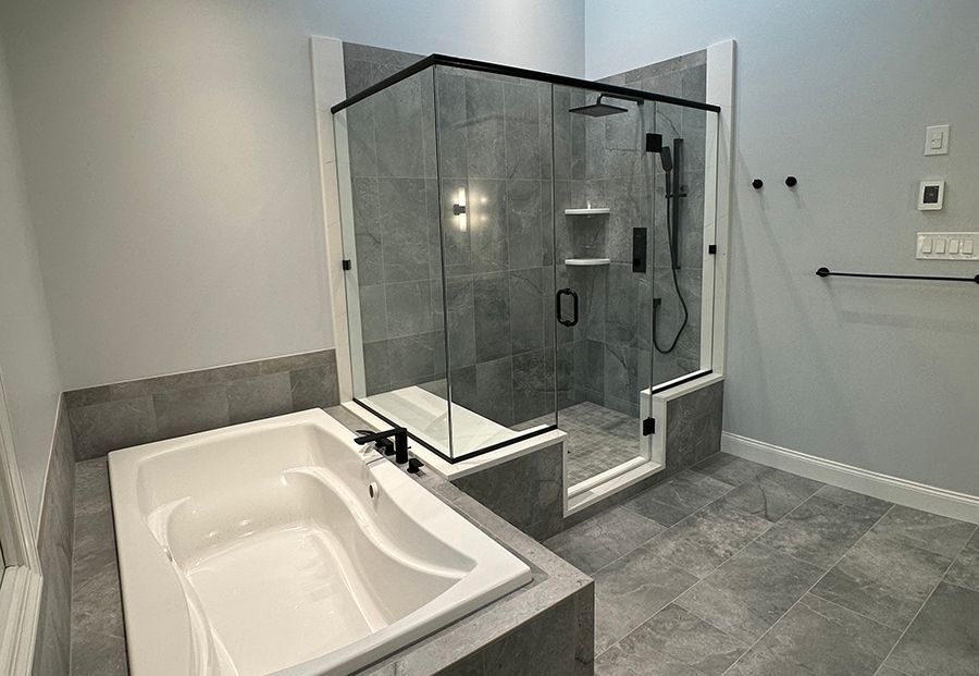Gray tile bathroom remodel with soaking tub and frameless glass shower