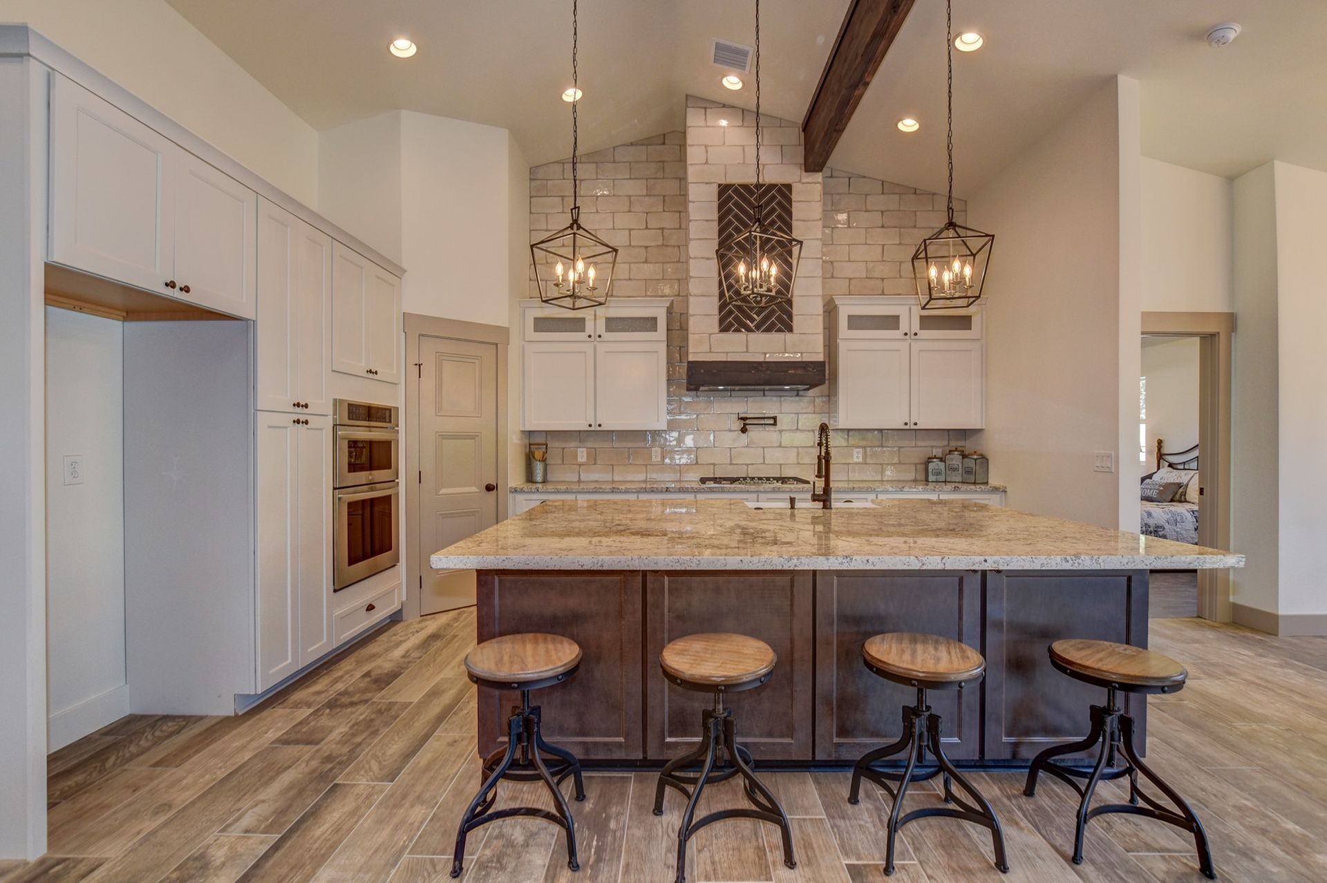 Kitchen with exposed beam, stone island, and lantern pendants