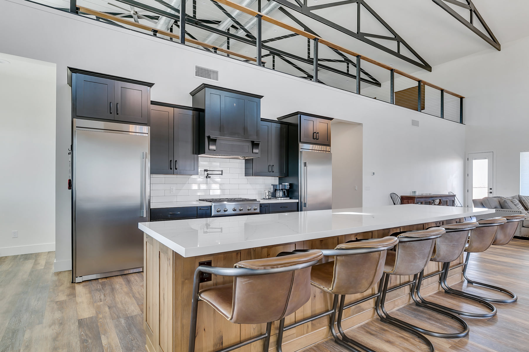 Kitchen with dark shaker cabinets, white quartz island, and leather counter stools