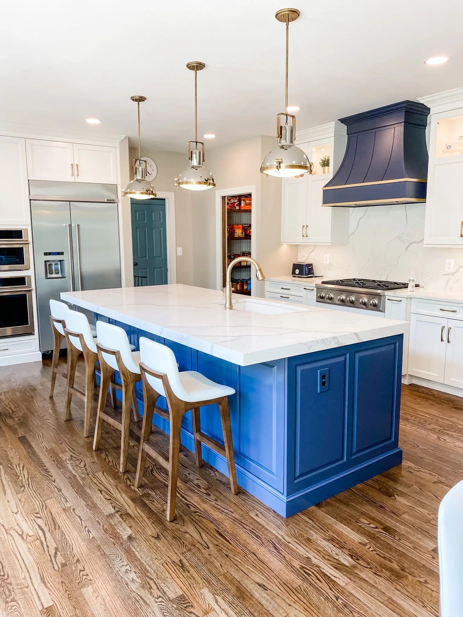 Kitchen remodel with navy island, quartz counters, and brass pendants